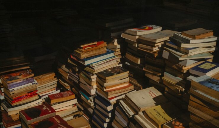 Photo of multiple stacks of books with the top and left portion of the picture heavily in shadow